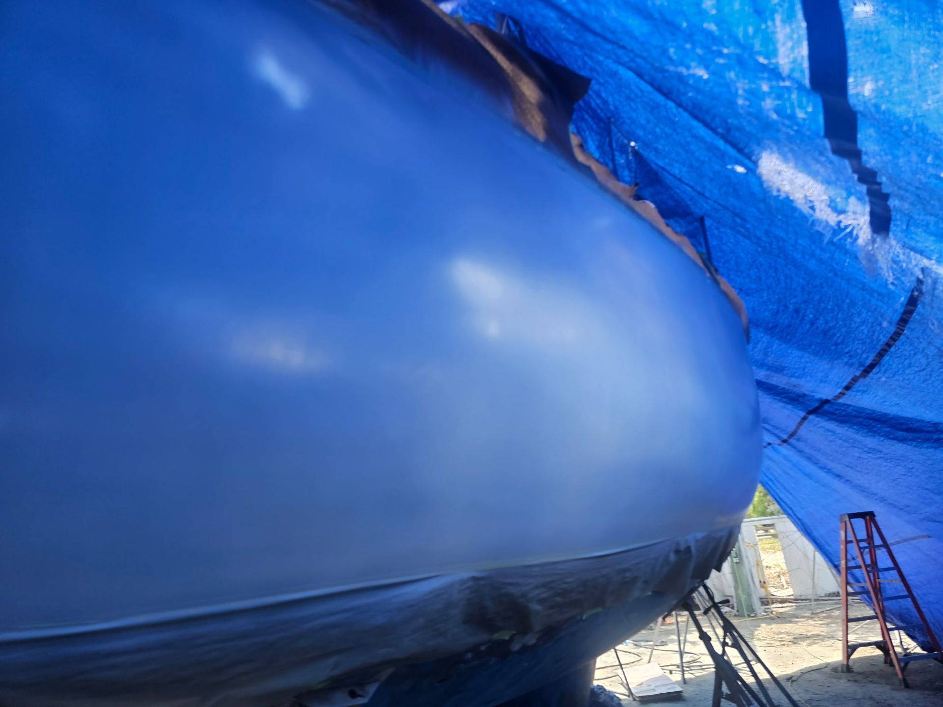 A boat is covered in a blue tarp.