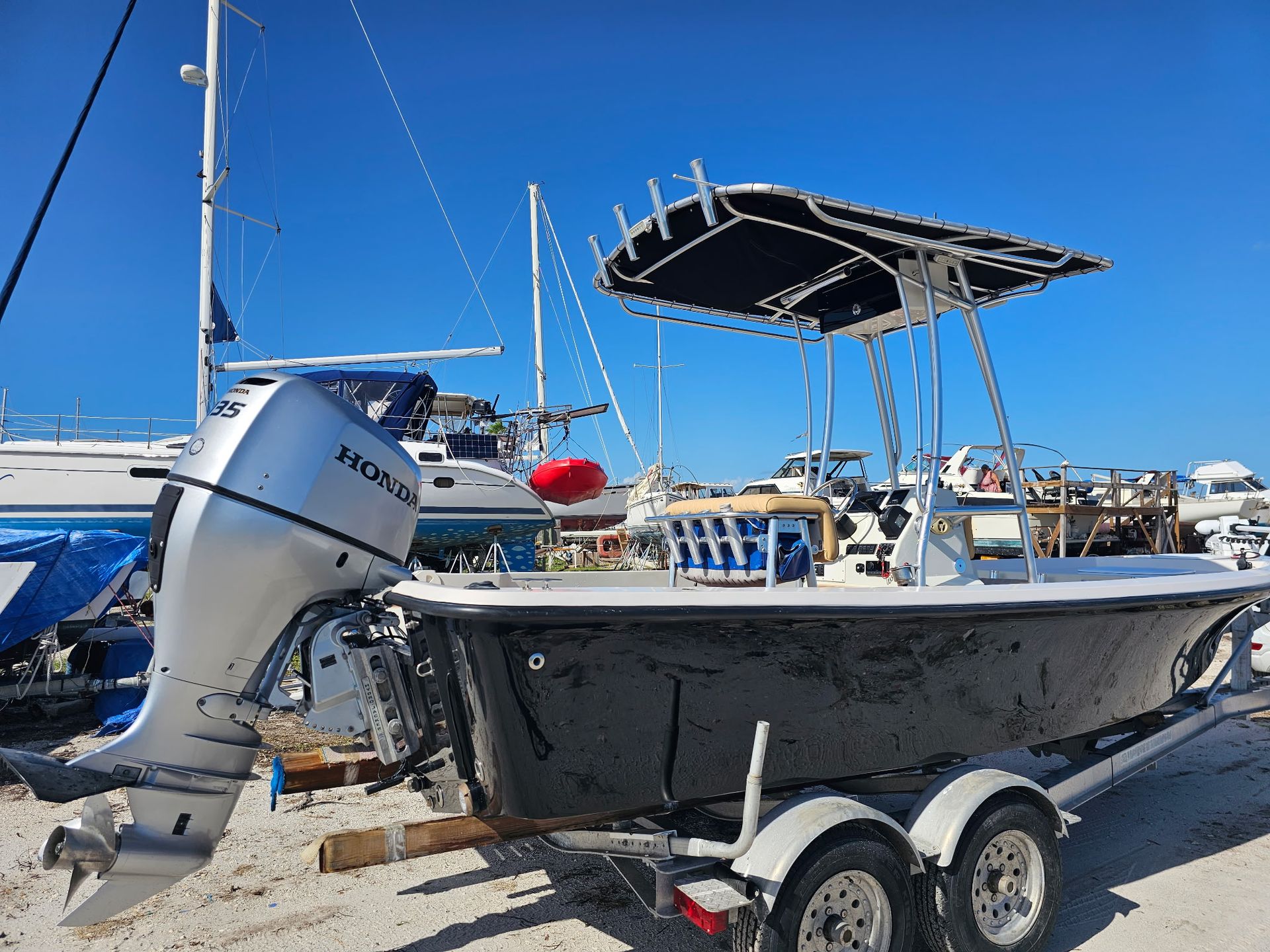 A boat with a honda outboard motor is parked on a trailer.
