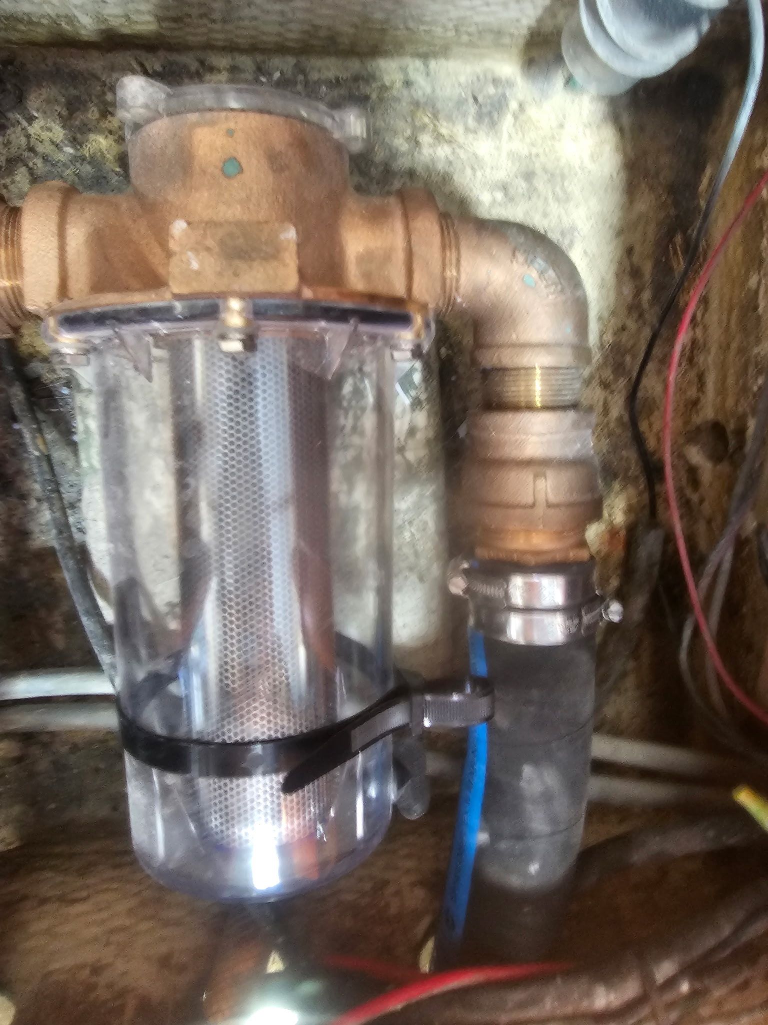 A close up of a brass pipe with a clear container attached to it.