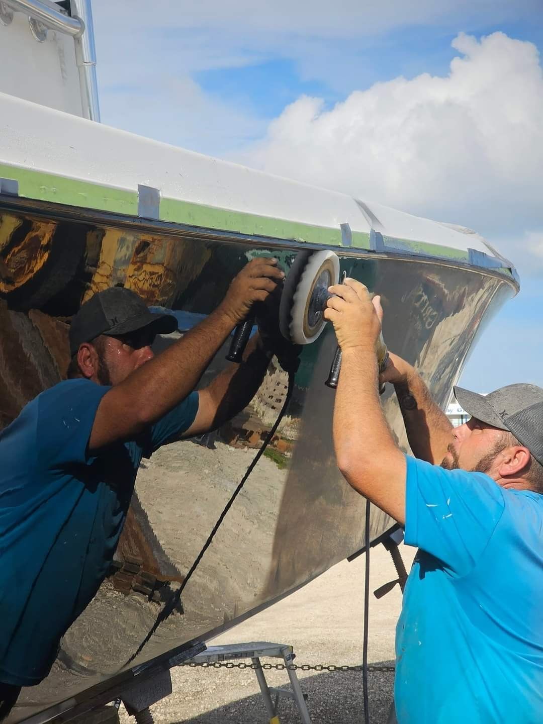 Two men are polishing a boat with a machine.