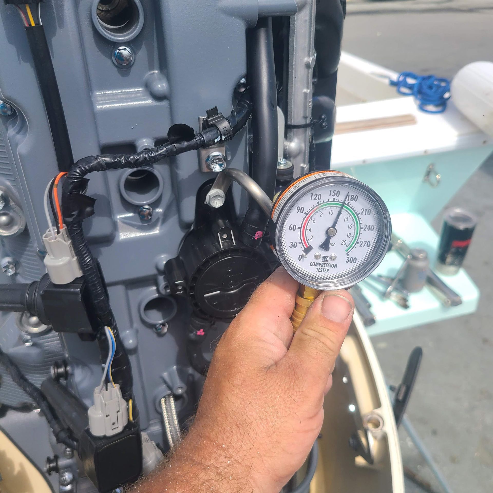 A man is holding a pressure gauge in front of a boat engine
