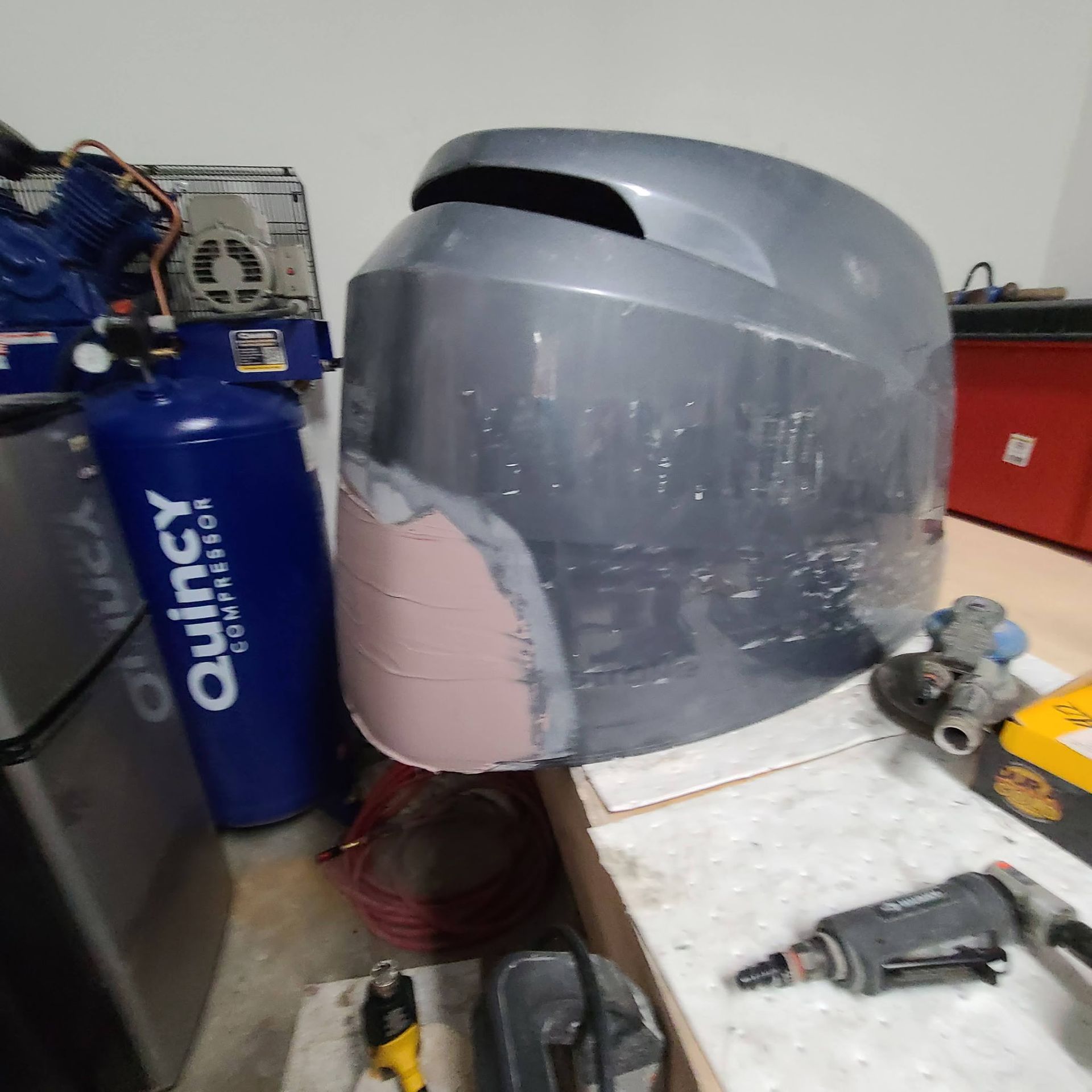A quincy air compressor is next to a helmet