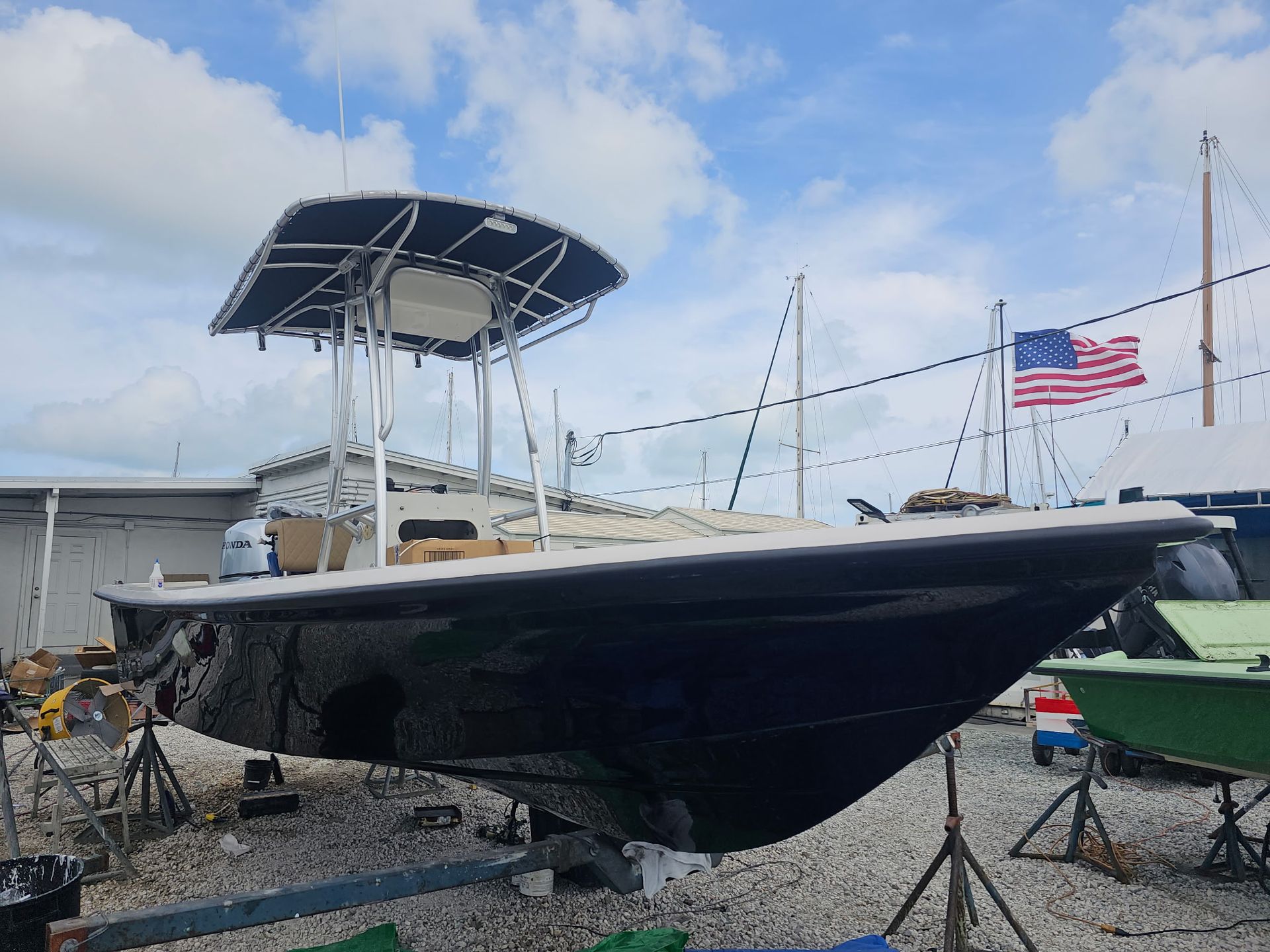 A boat is sitting on a trailer in a lot with an american flag in the background.