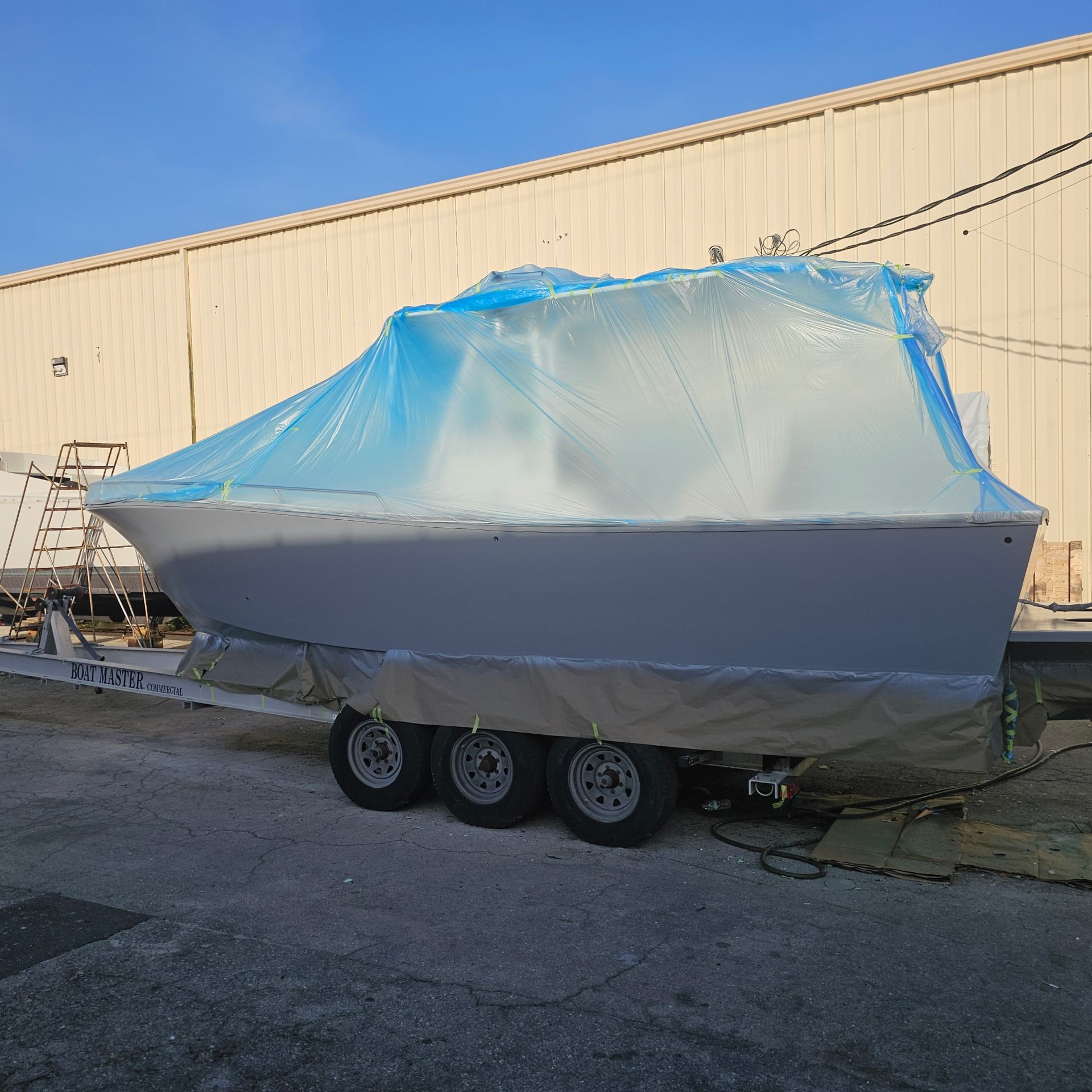 A boat is wrapped in plastic and is on a trailer