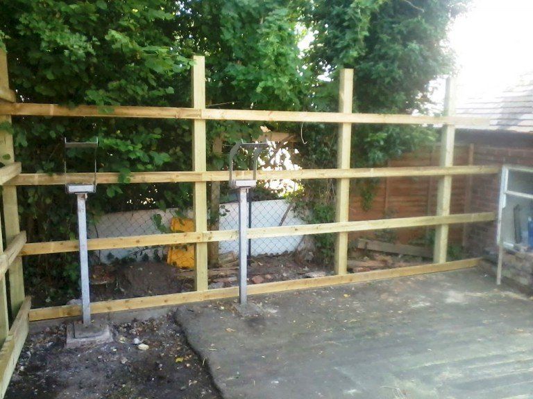 A wooden fence is being built in a backyard