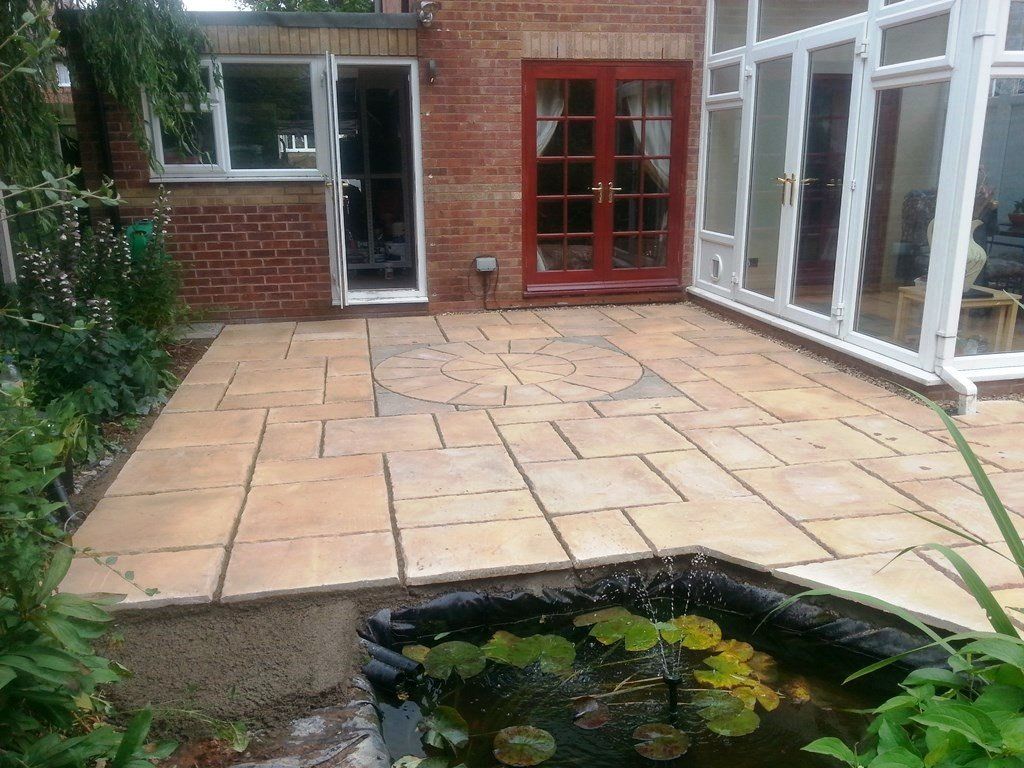 A patio with a pond and a brick building in the background