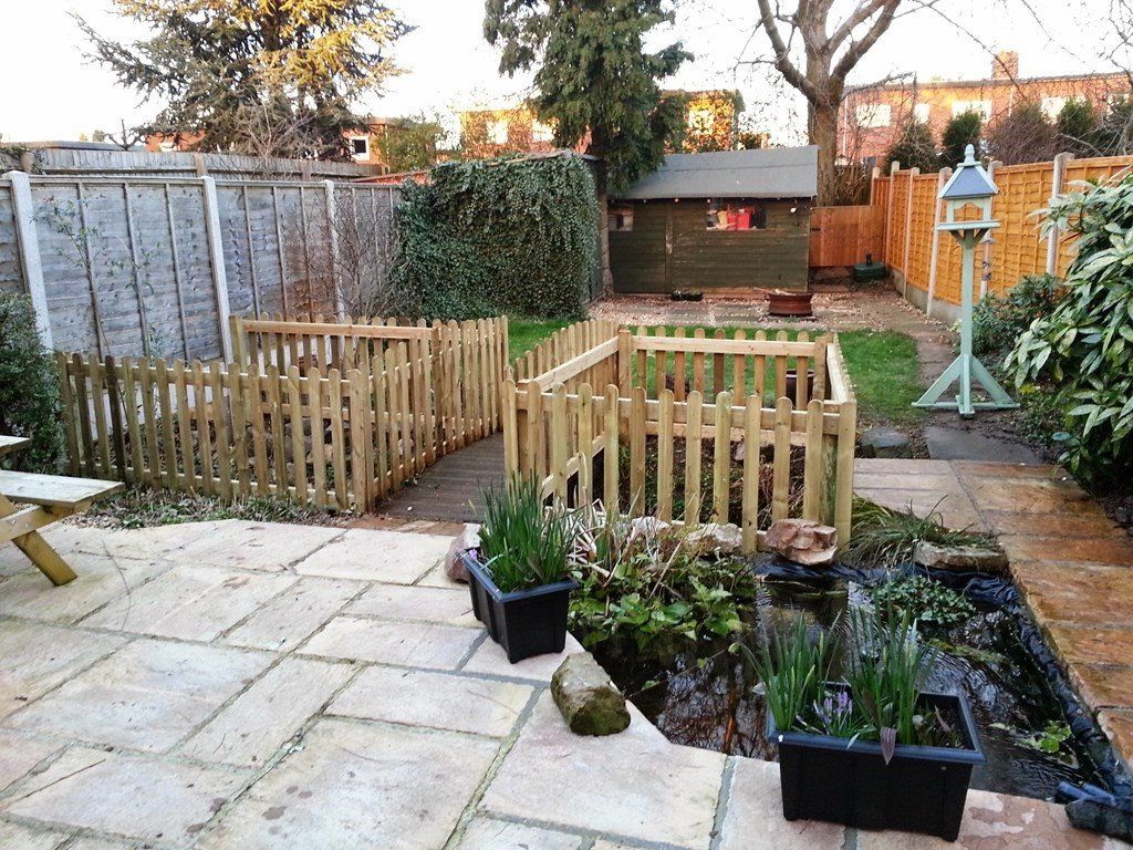 A garden with a wooden fence and a pond