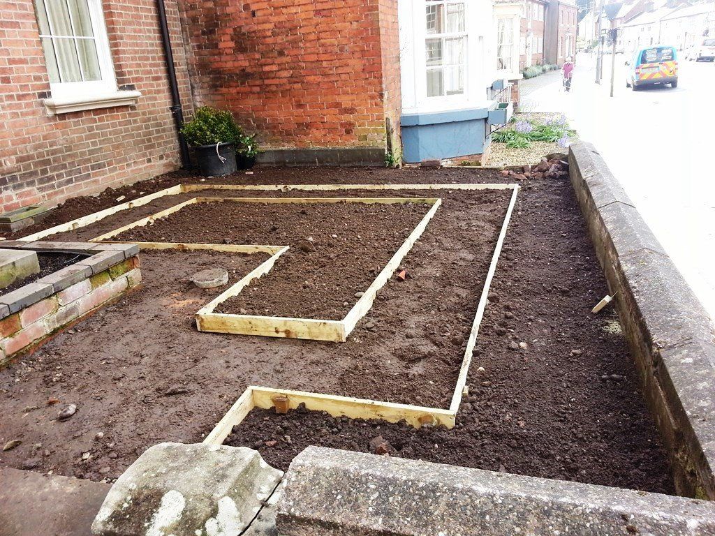 A garden is being built in front of a brick building.