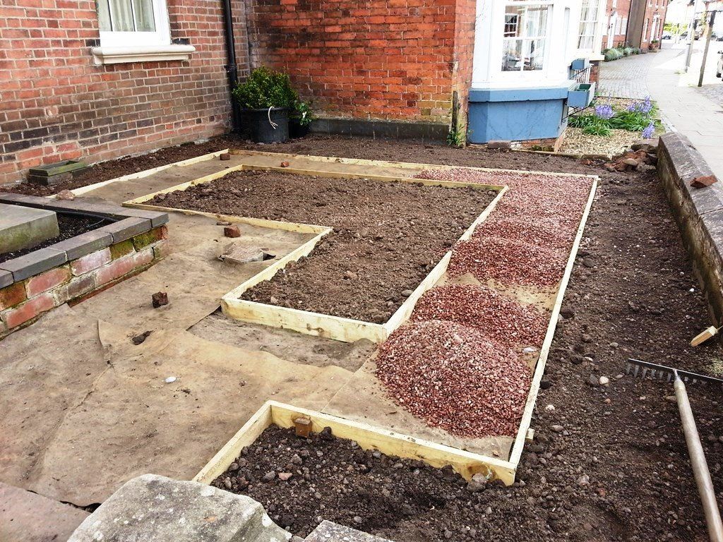 A garden is being built in front of a brick building.