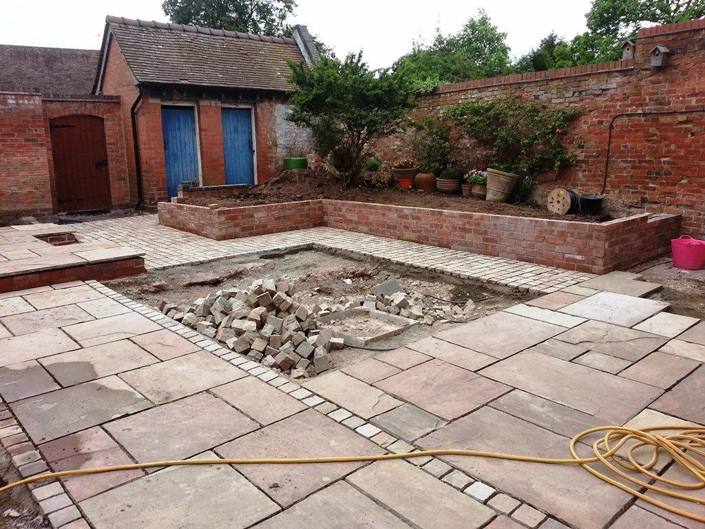 A brick building is being built in the backyard of a house.