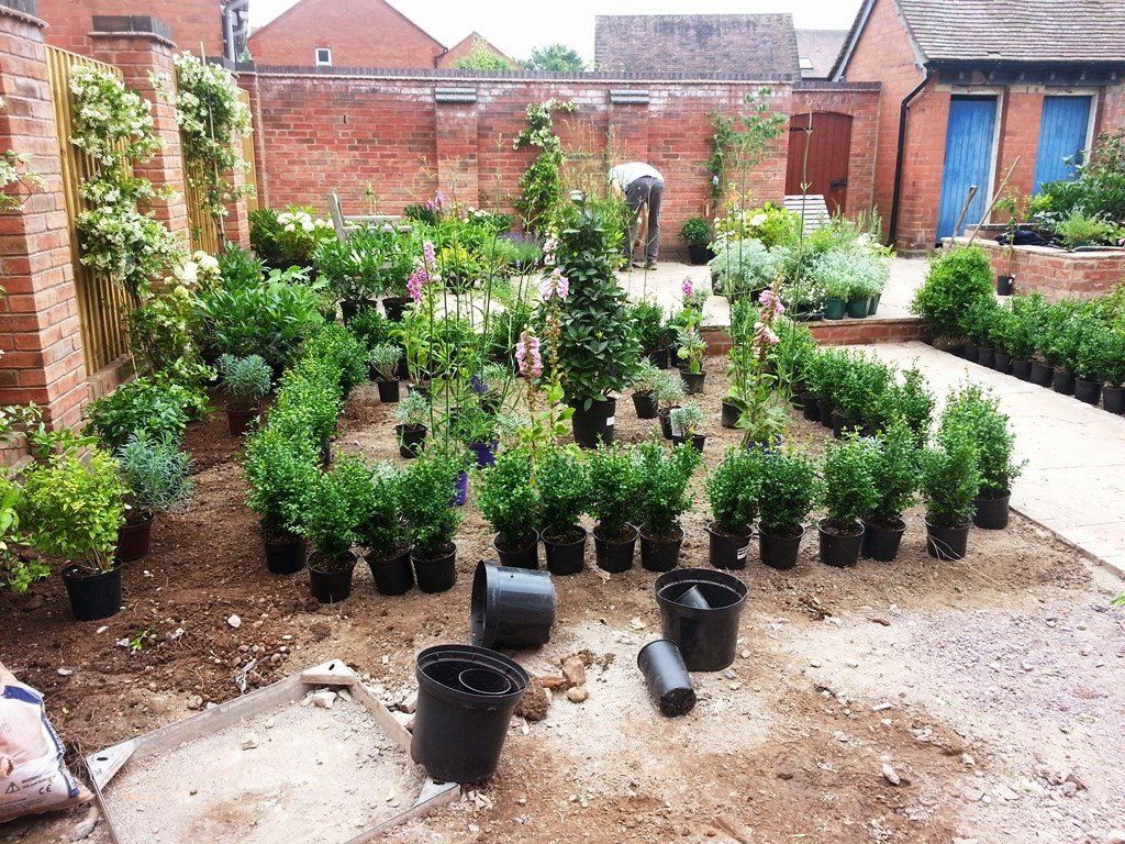 A garden filled with lots of potted plants and a brick wall.