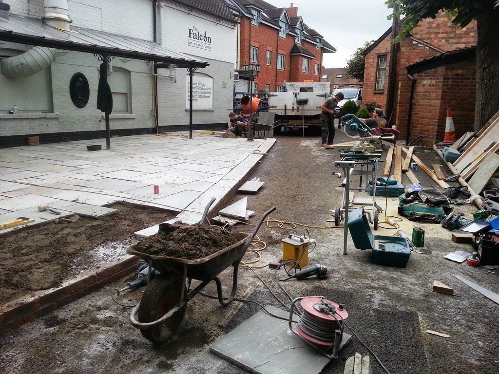A wheelbarrow filled with dirt is sitting on the ground in front of a building under construction.