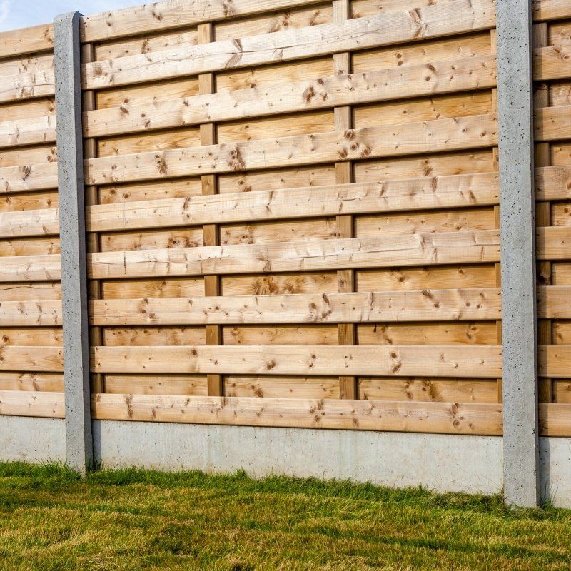 A wooden fence surrounds a lush green field