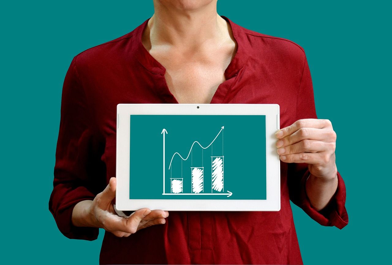 A woman in a red shirt is holding a tablet with a graph on it