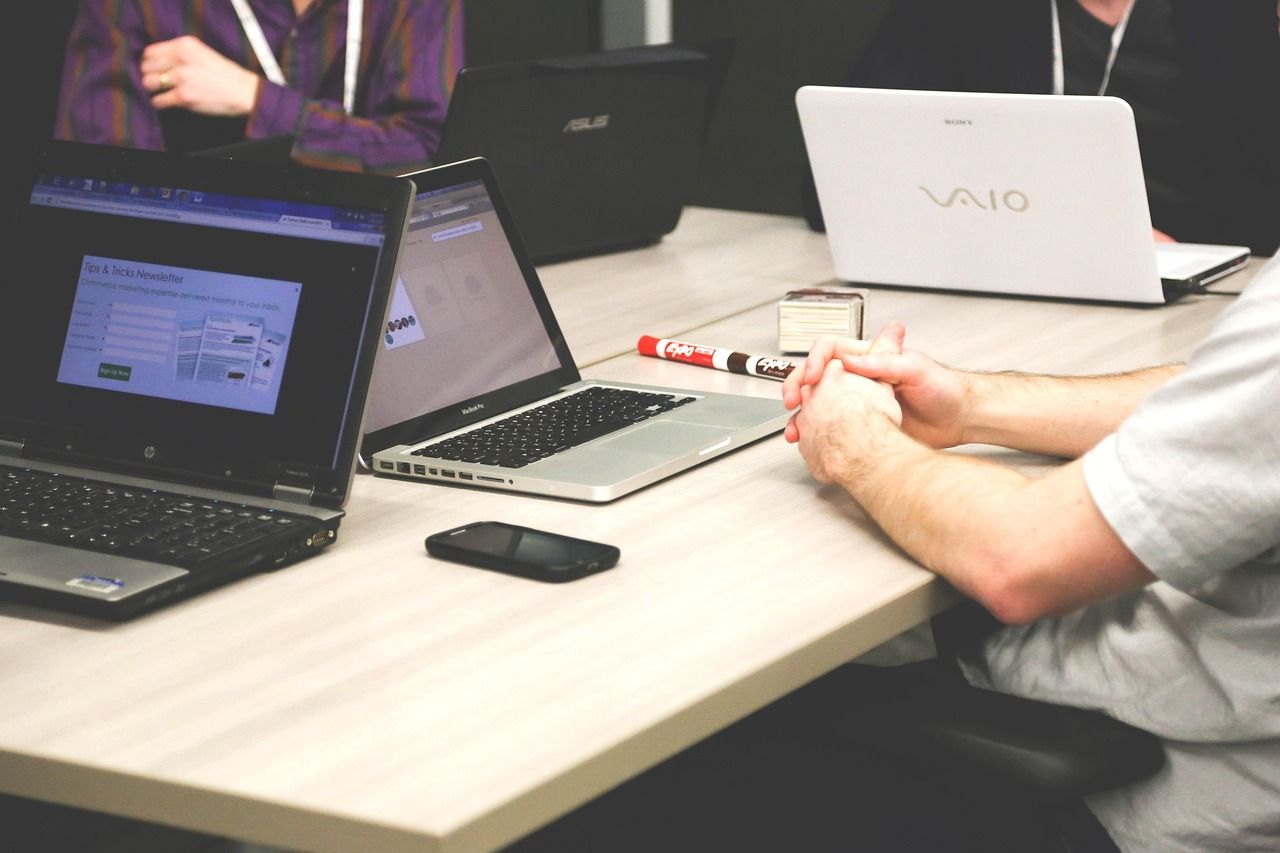 Several people meet at a table with laptops