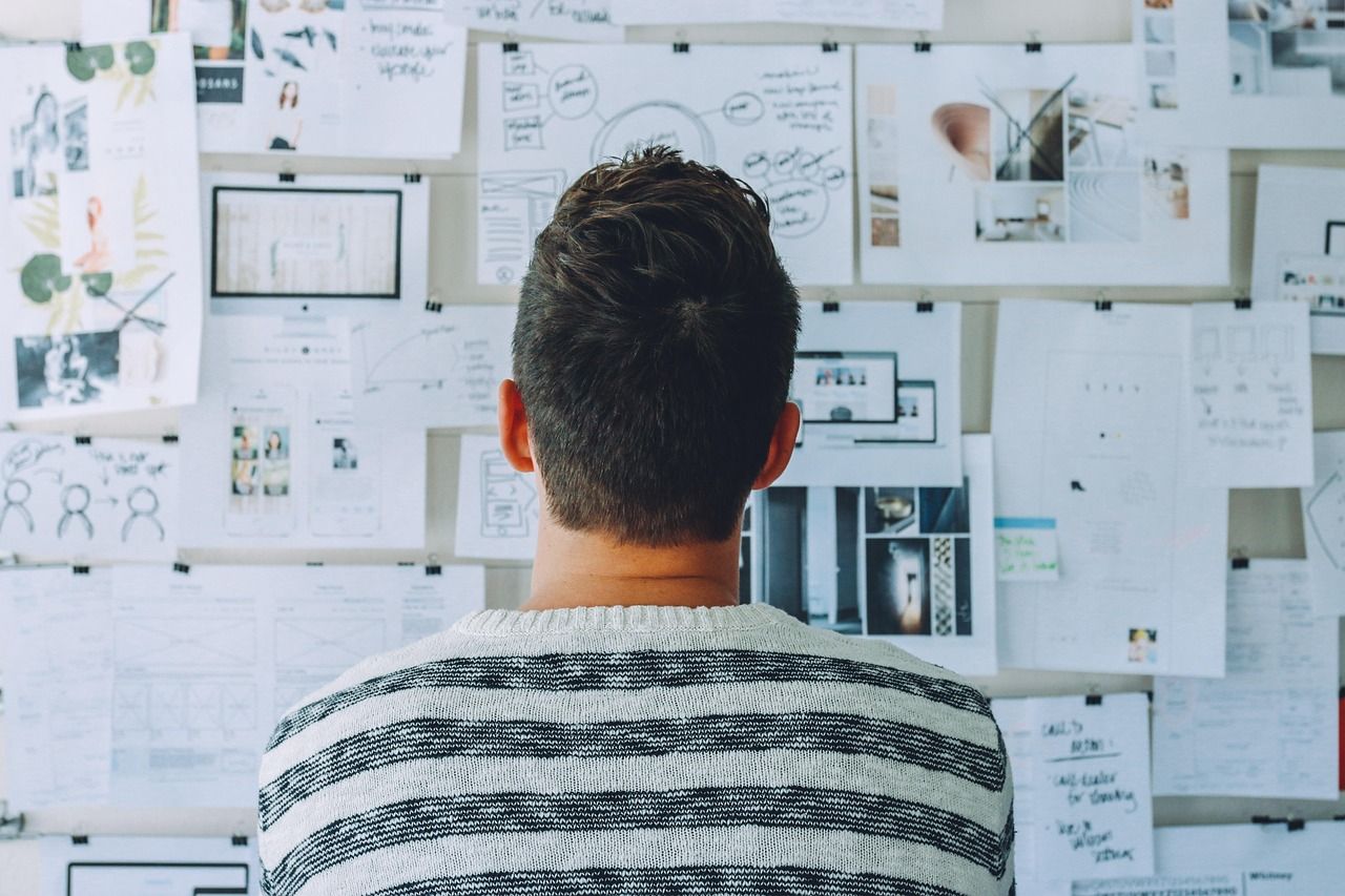 A man is looking at a whiteboard full of papers.