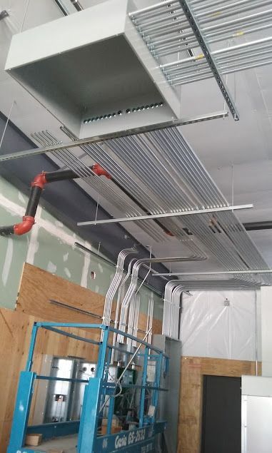 Construction site with electrical conduit, ductwork, and lift in progress.