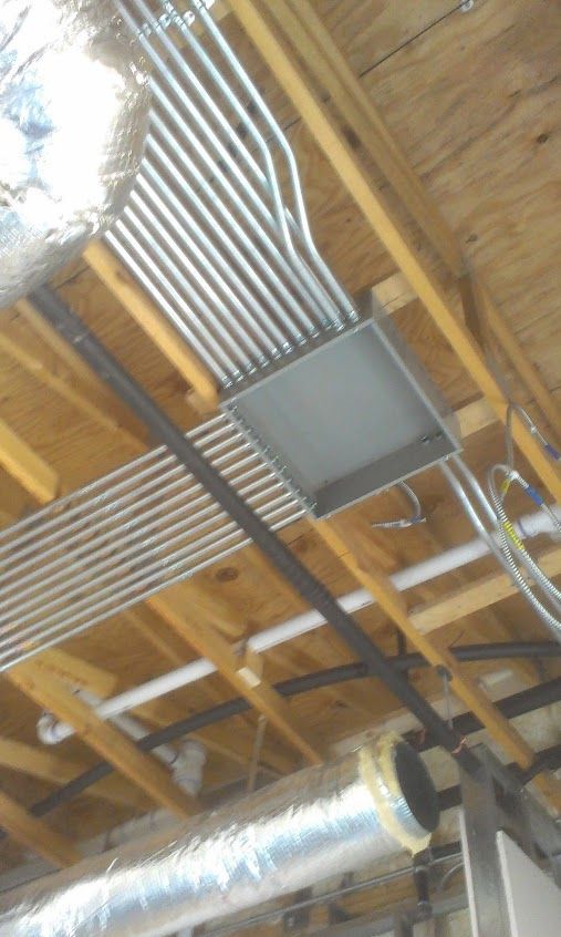 Electrical conduits and box installed on a wooden ceiling in a building's attic.