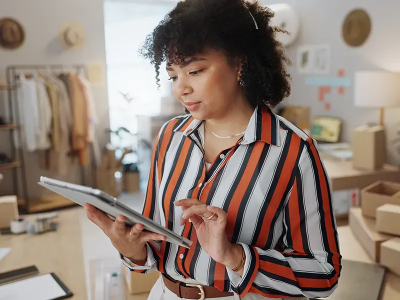 Una mujer con una camisa de rayas está usando una tableta.