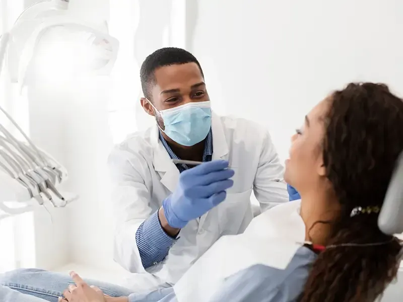 Un dentista está examinando los dientes de una mujer en un consultorio dental.