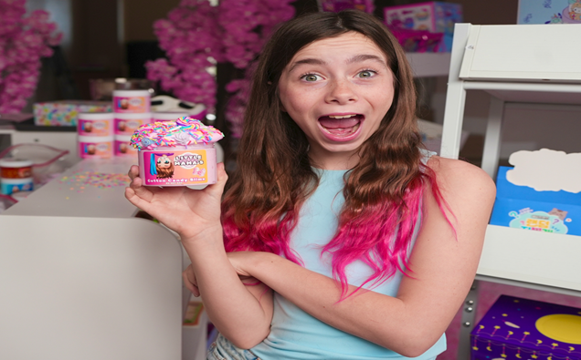 Woman smiling and holding a colorful ice cream tub in a bright dessert shop
