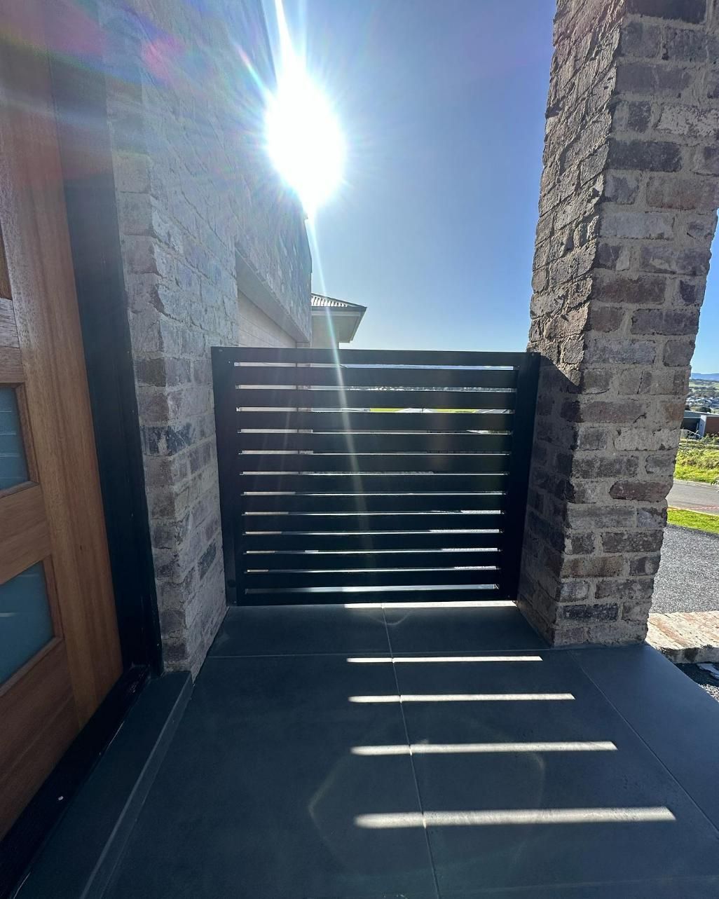 A Brick Wall with A Gate in Front of It — Optimum Aluminium Fabrication in Barrack Heights, NSW