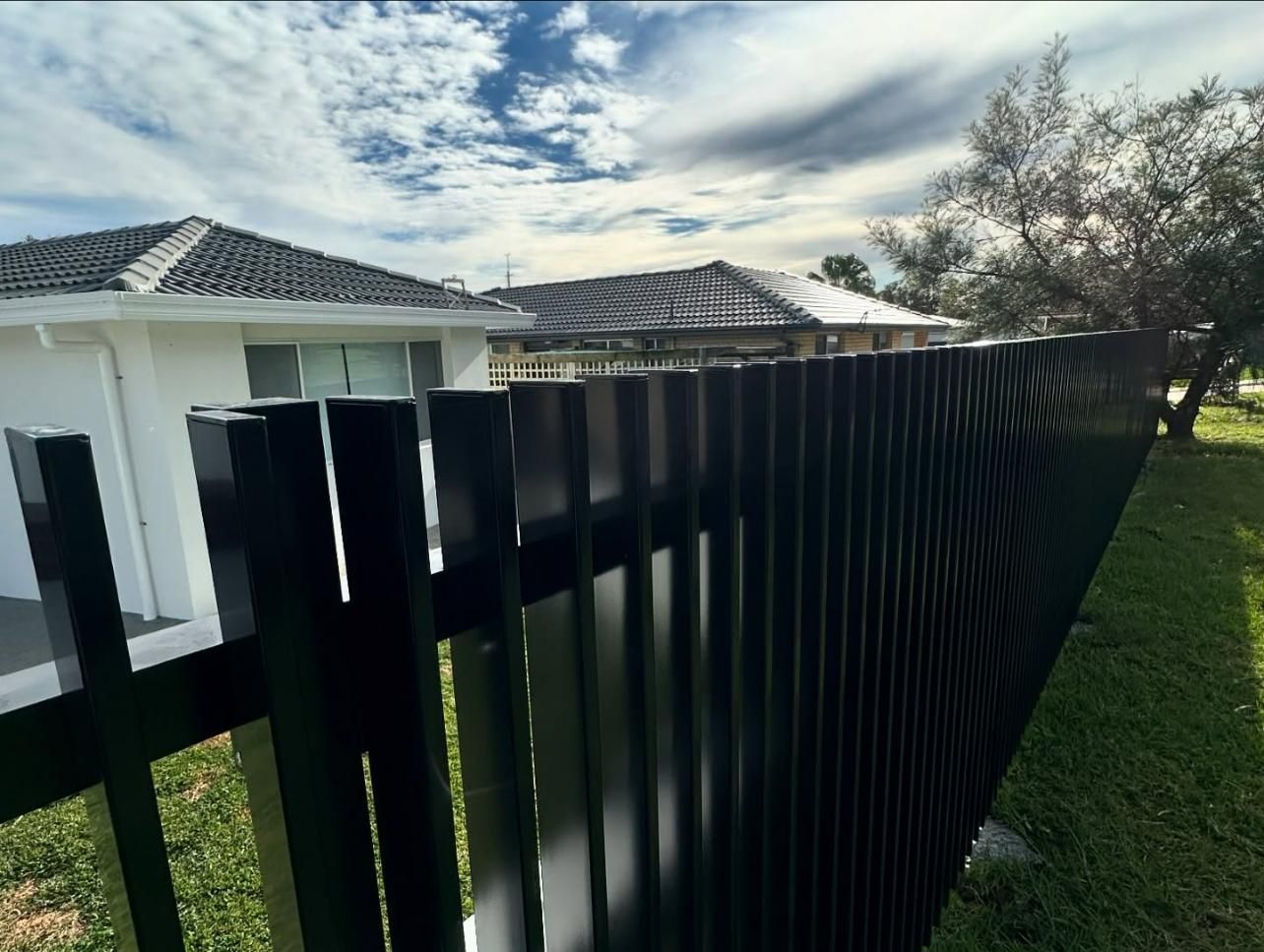 A Black Fence Is in Front of A White House — Optimum Aluminium Fabrication in Barrack Heights, NSW