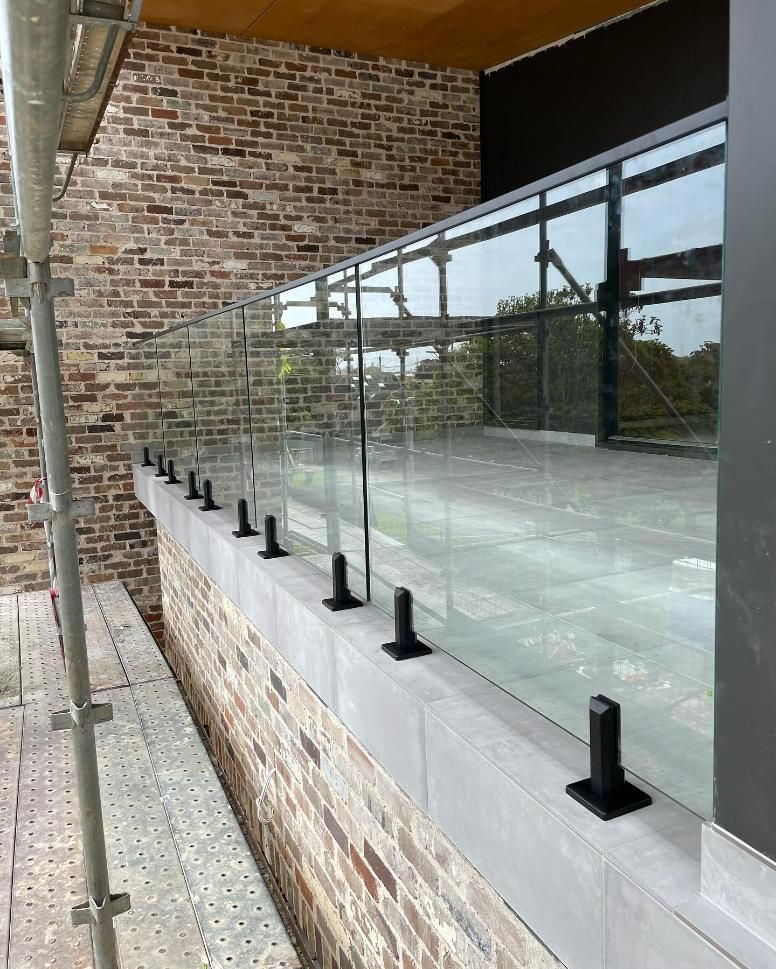A Brick Building with A Glass Railing on The Side of It — Optimum Aluminium Fabrication in Barrack Heights, NSW