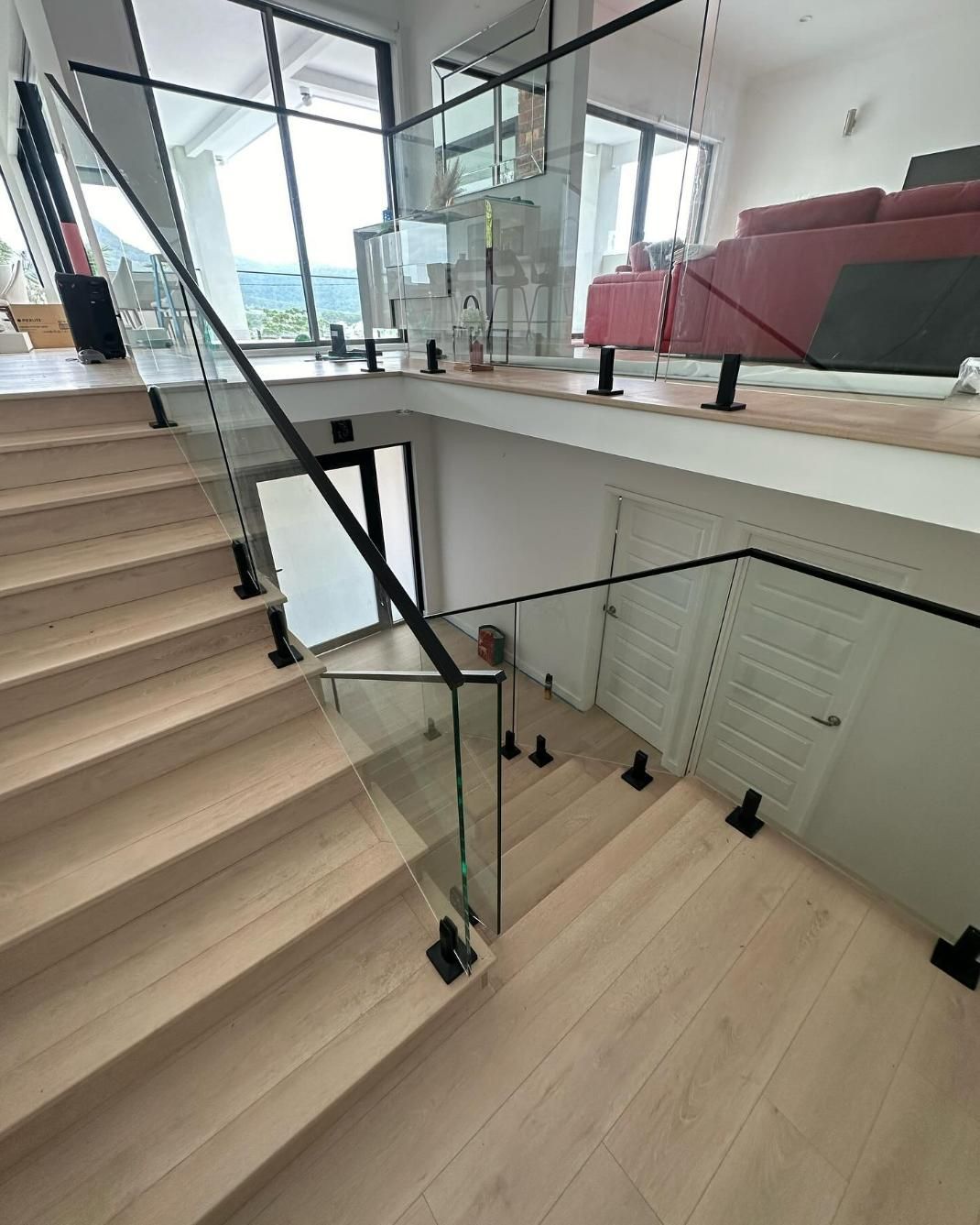 A Wooden Staircase with A Glass Railing in A Living Room — Optimum Aluminium Fabrication in Barrack Heights, NSW