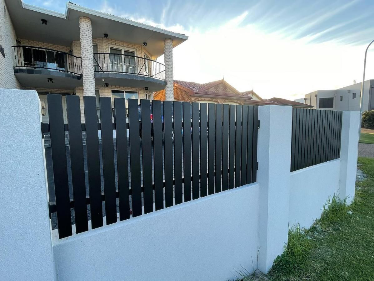 A White Wall with A Black Fence in Front of A House — Optimum Aluminium Fabrication in Barrack Heights, NSW