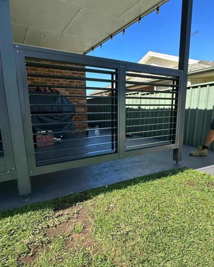 A Man Is Standing in Front of A Fence with A Grill in The Background — Optimum Aluminium Fabrication in Barrack Heights, NSW