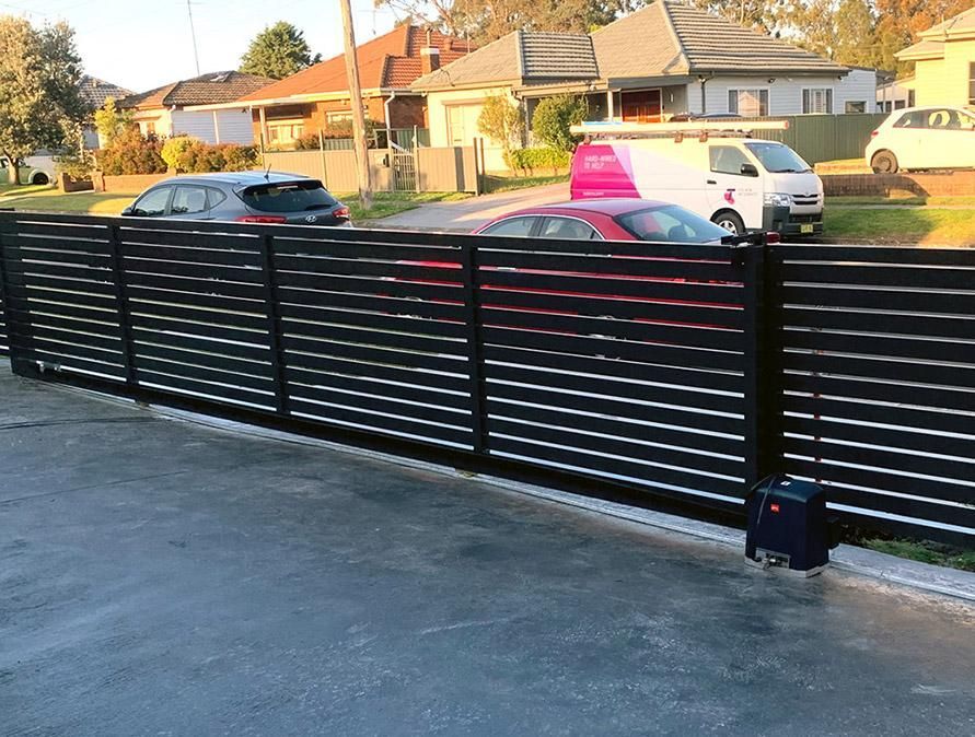 A Black Fence with Cars Parked in Front of It — Optimum Aluminium Fabrication in Barrack Heights, NSW