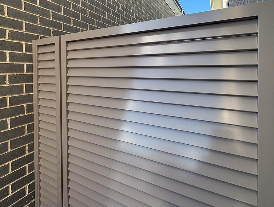 A Fence with Shutters on It Is Next to A Brick Wall — Optimum Aluminium Fabrication in Barrack Heights, NSW