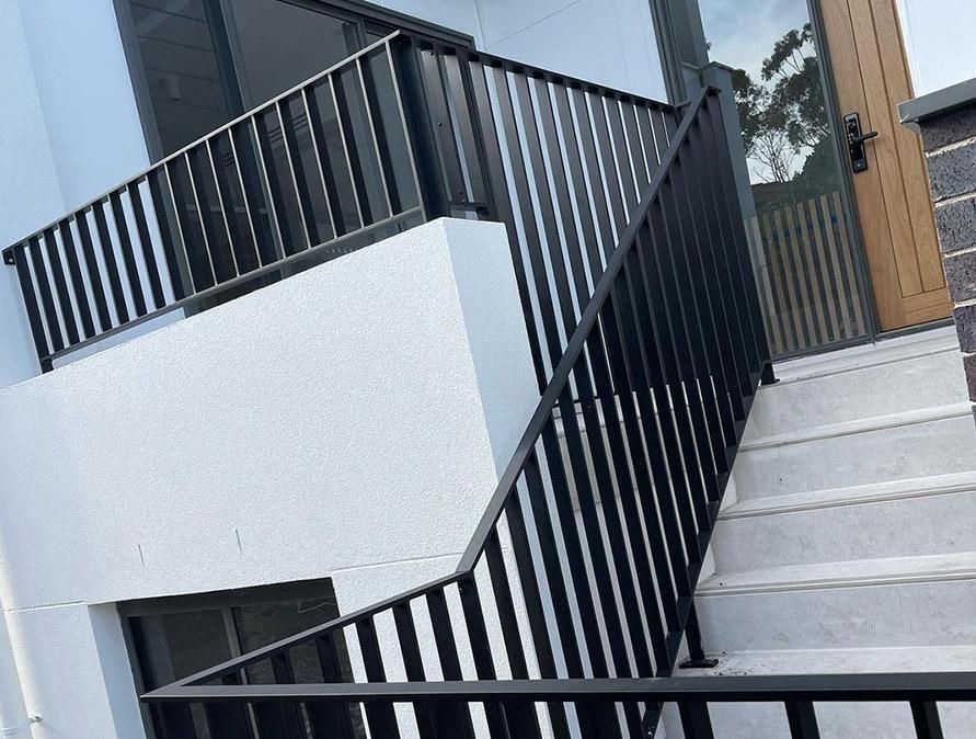 A Set of Stairs with A Black Railing and A Wooden Door — Optimum Aluminium Fabrication in Barrack Heights, NSW