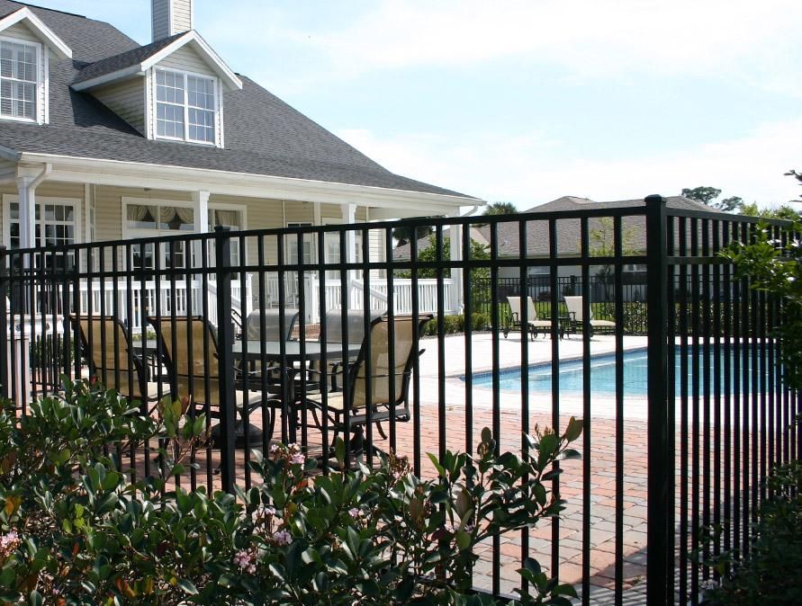 A Black Fence Surrounds a Swimming Pool in Front of A House — Optimum Aluminium Fabrication in Barrack Heights, NSW