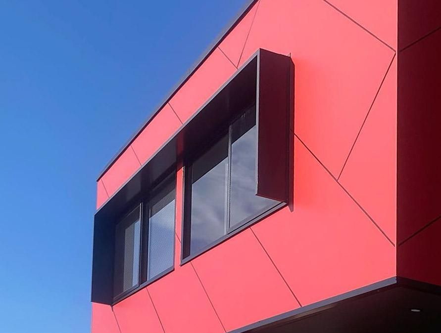 A Red Building with Black Windows Against a Blue Sky — Optimum Aluminium Fabrication in Barrack Heights, NSW
