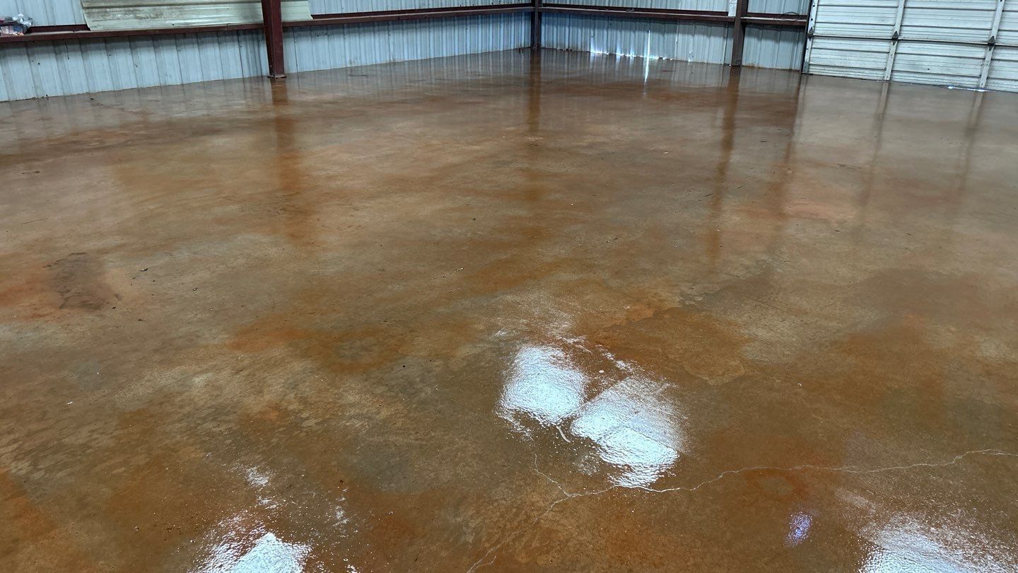 Brown, glossy concrete floor reflecting the interior of a warehouse.