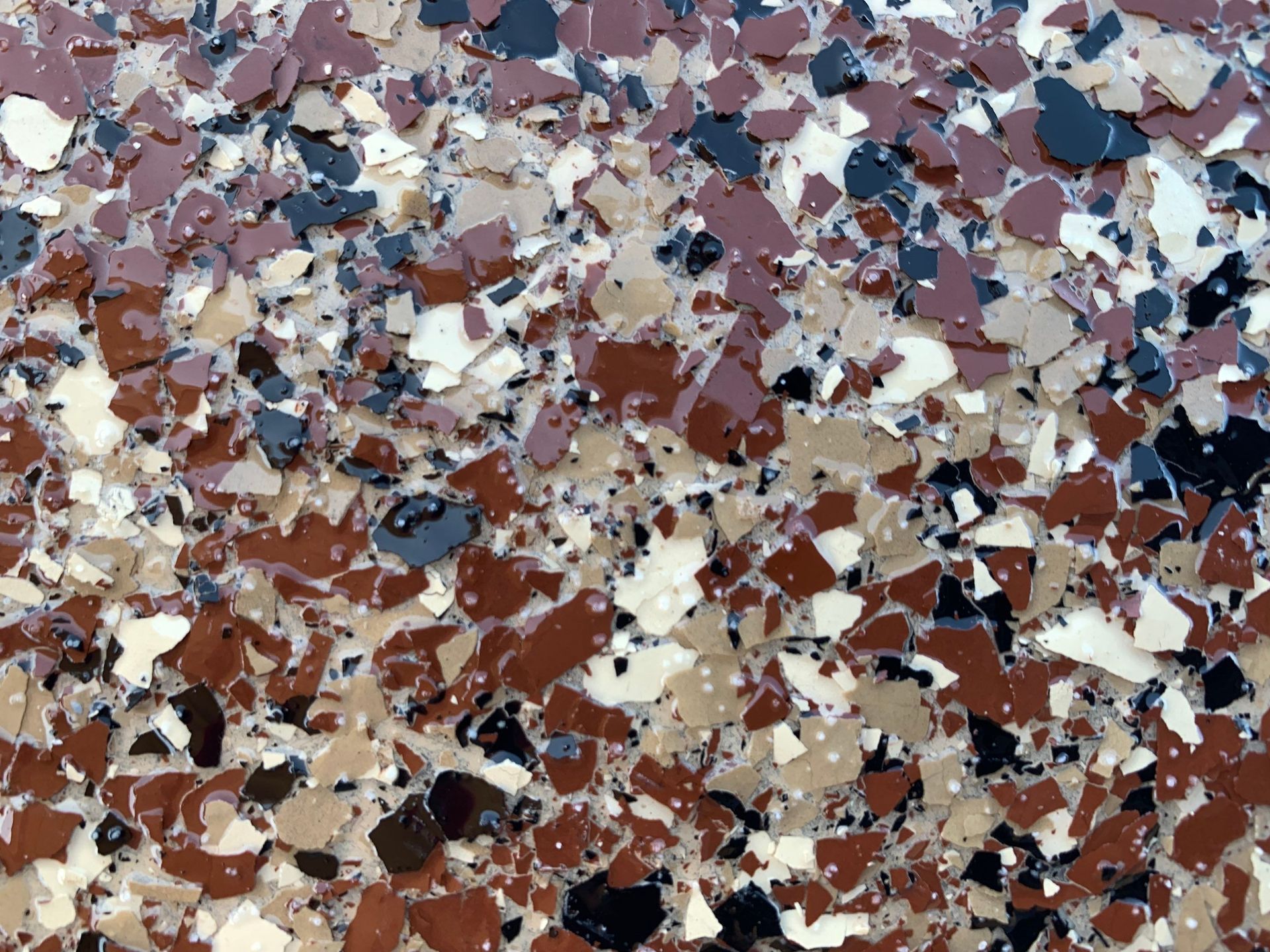 Epoxy floor with a speckled pattern of brown, black, tan, and cream colored chips.