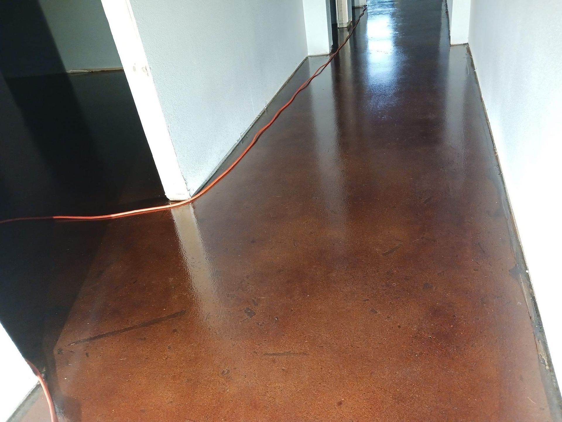 Brown stained concrete hallway with a cord running across the floor.