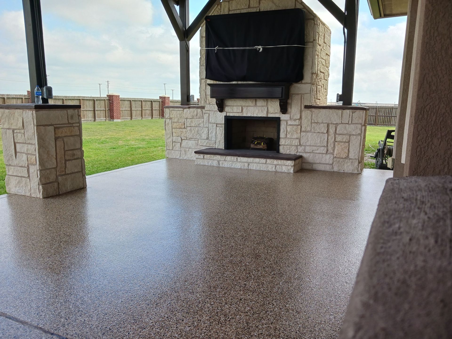 Outdoor patio with a fireplace and shiny, speckled flooring.