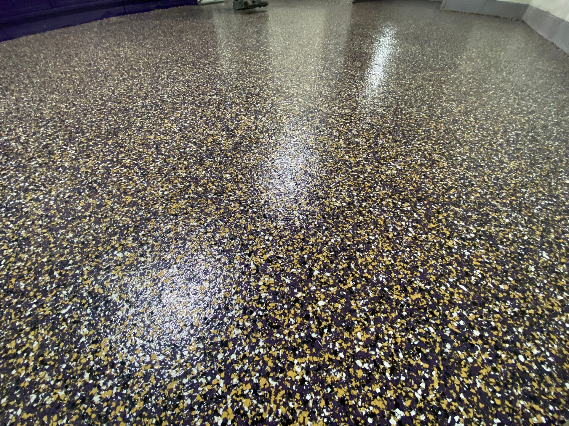 Epoxy floor with black, gold, and white flecks, reflecting light.