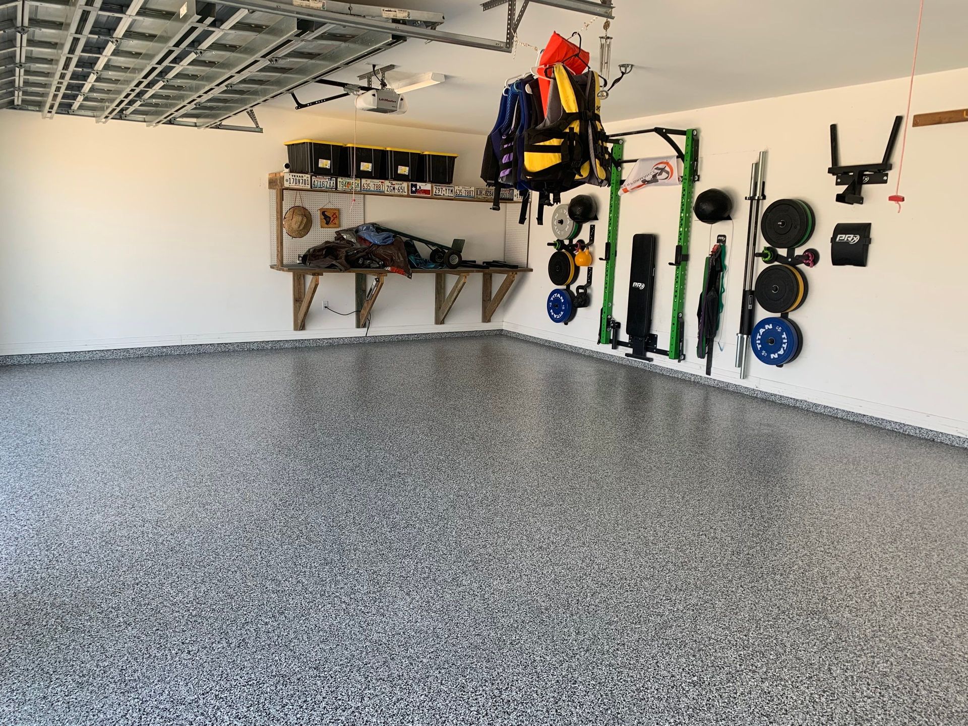 Garage with epoxy floor, workout equipment on wall, and storage shelves.