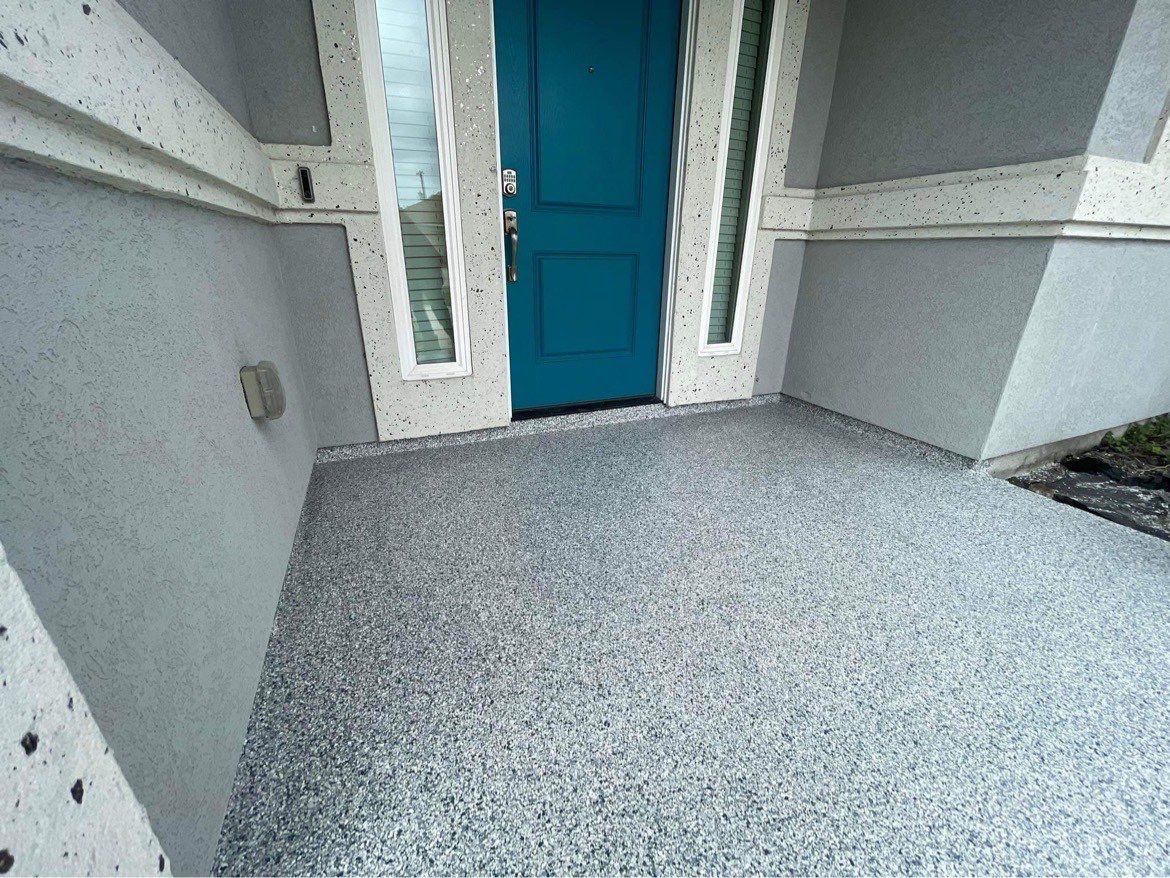Gray speckled concrete porch with a teal door.
