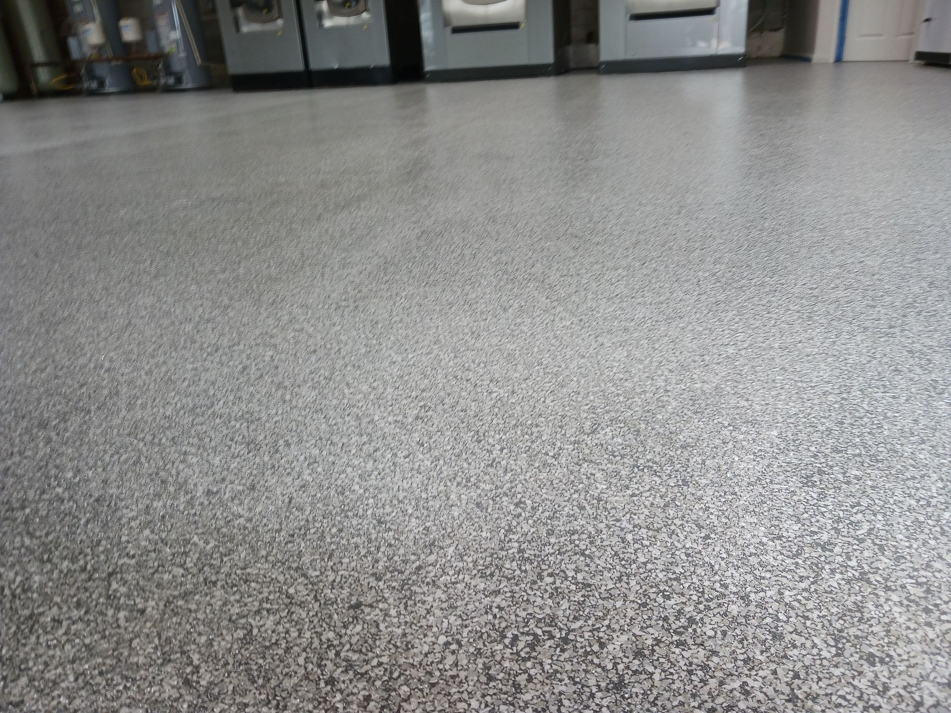 Gray speckled epoxy floor with industrial equipment in the background.