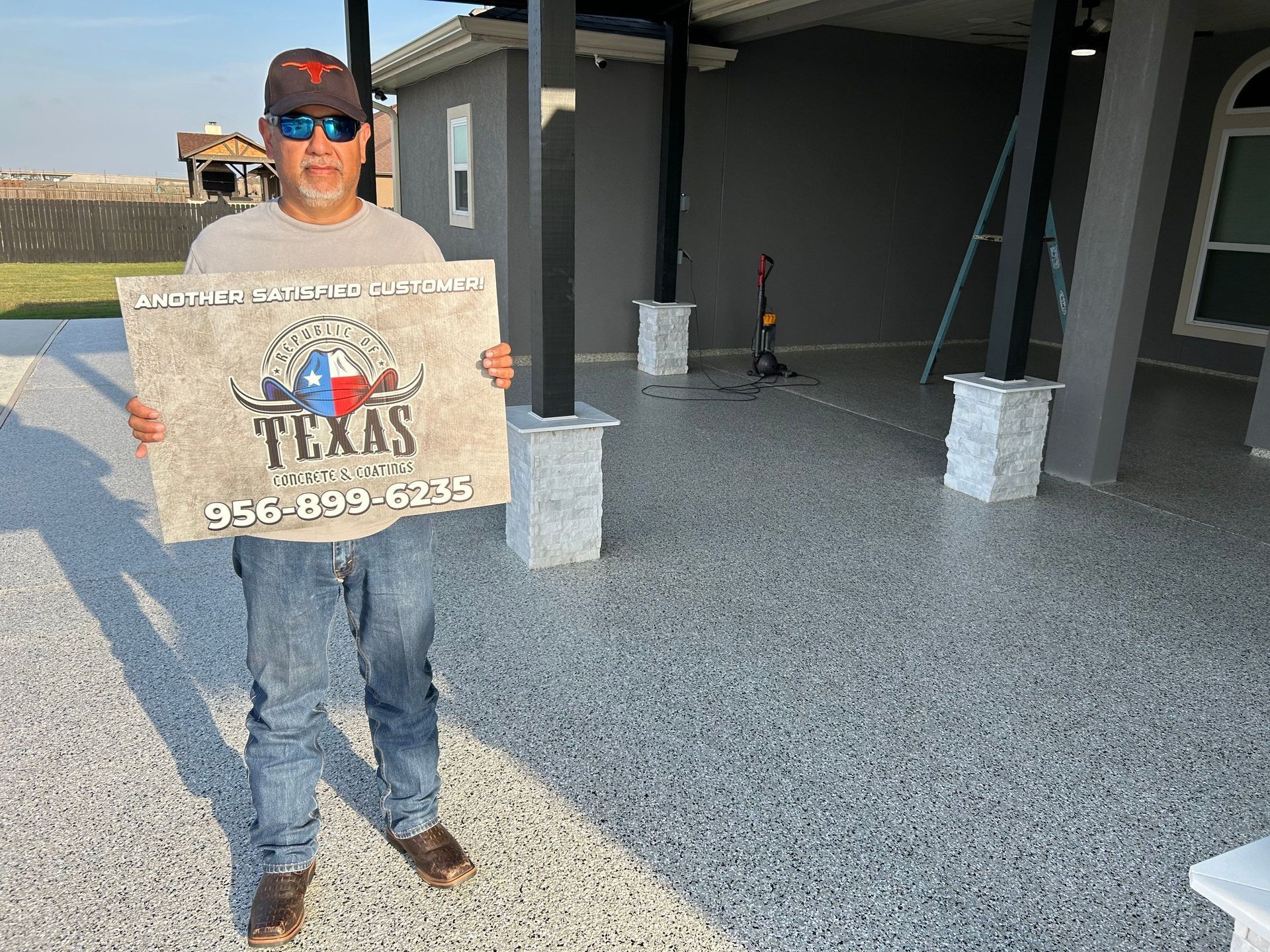 Man holding sign for Texas Concrete Solutions stands on speckled concrete patio.