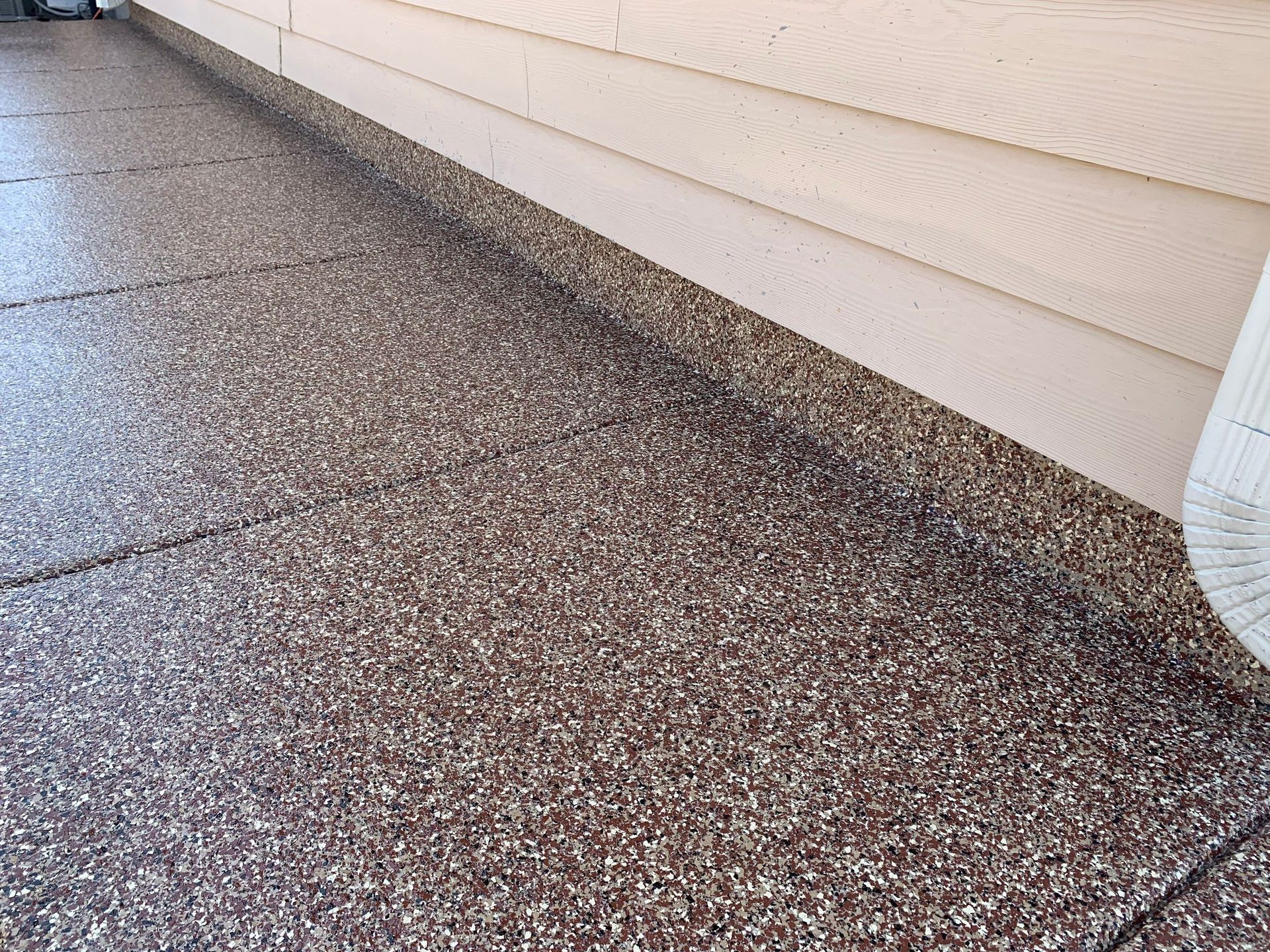 Granite-like speckled flooring next to beige siding of a building.