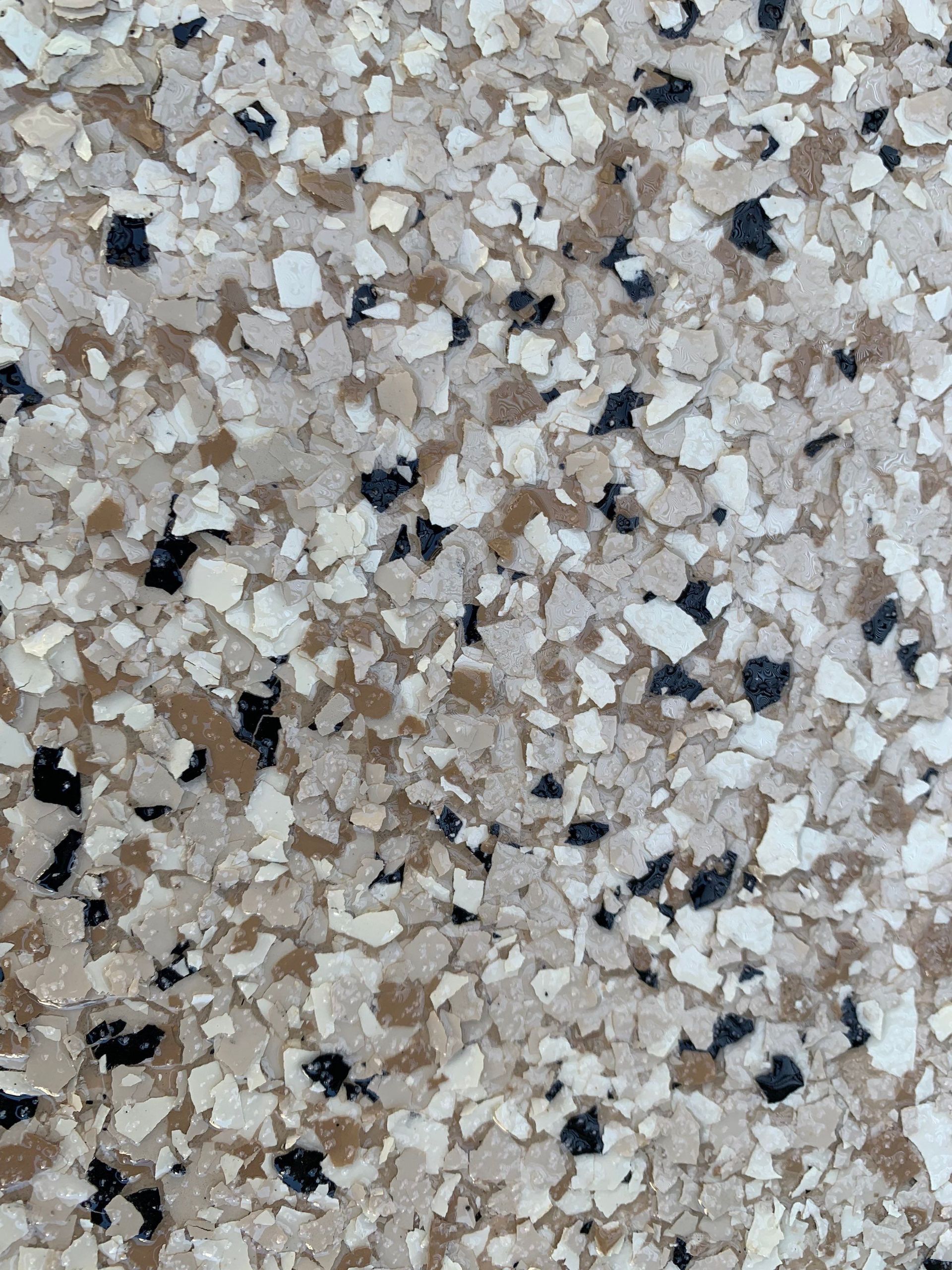 Close-up of a speckled floor with tan, beige, brown, and black chips.