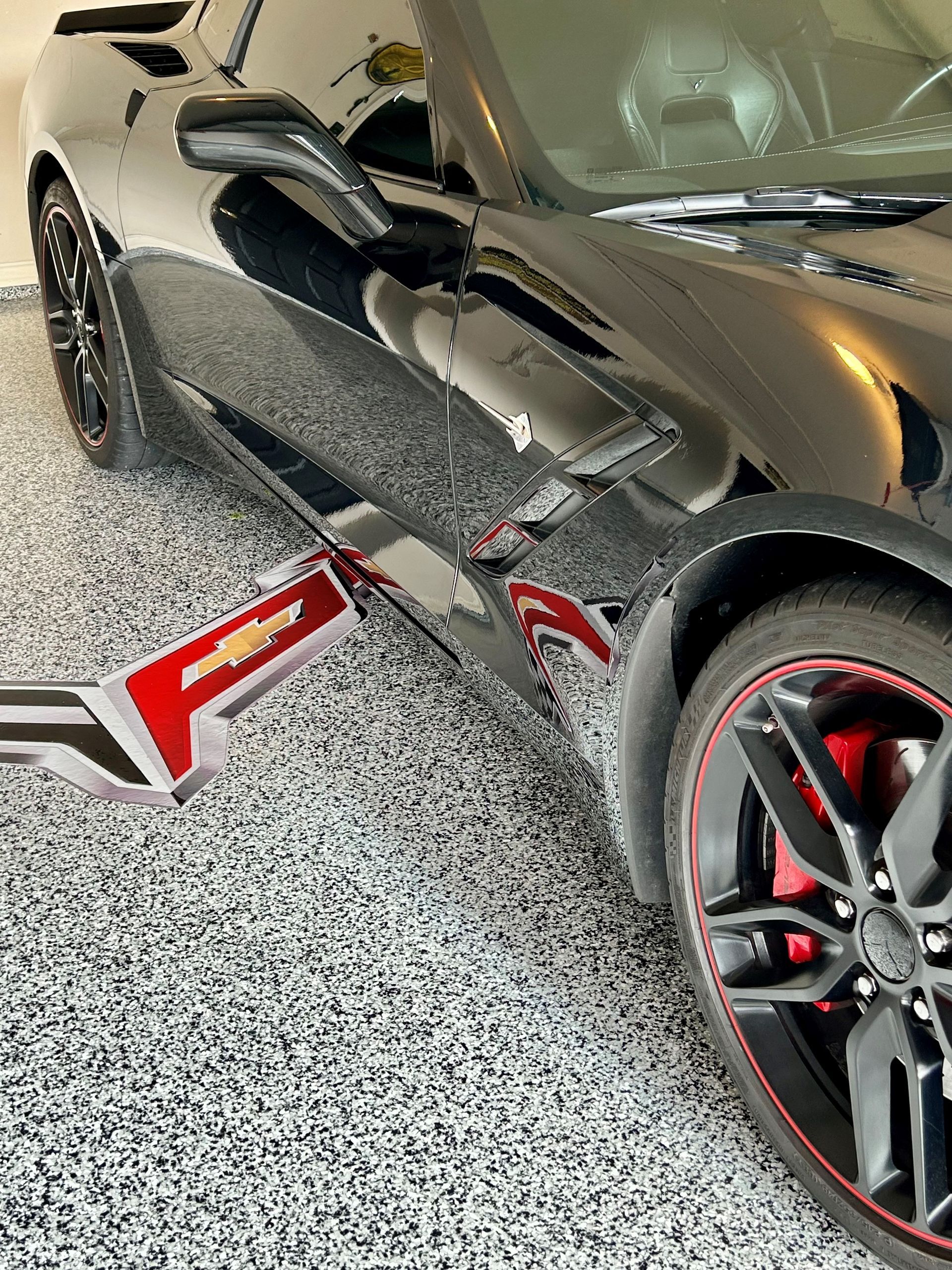 Black Corvette sports car with red accents in a garage.