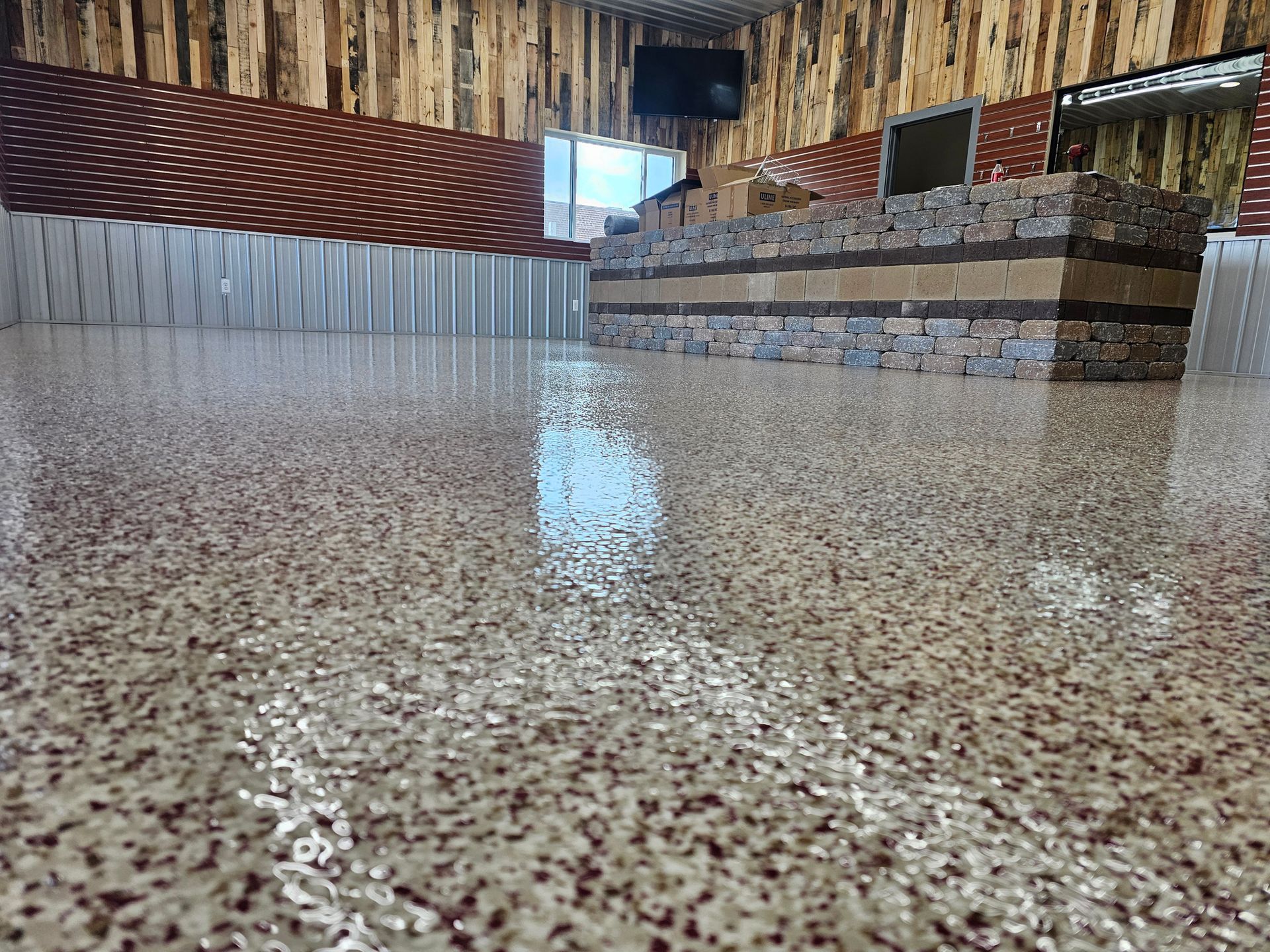 Close-up of a glossy speckled floor in a modern room with wood walls and stone counter.