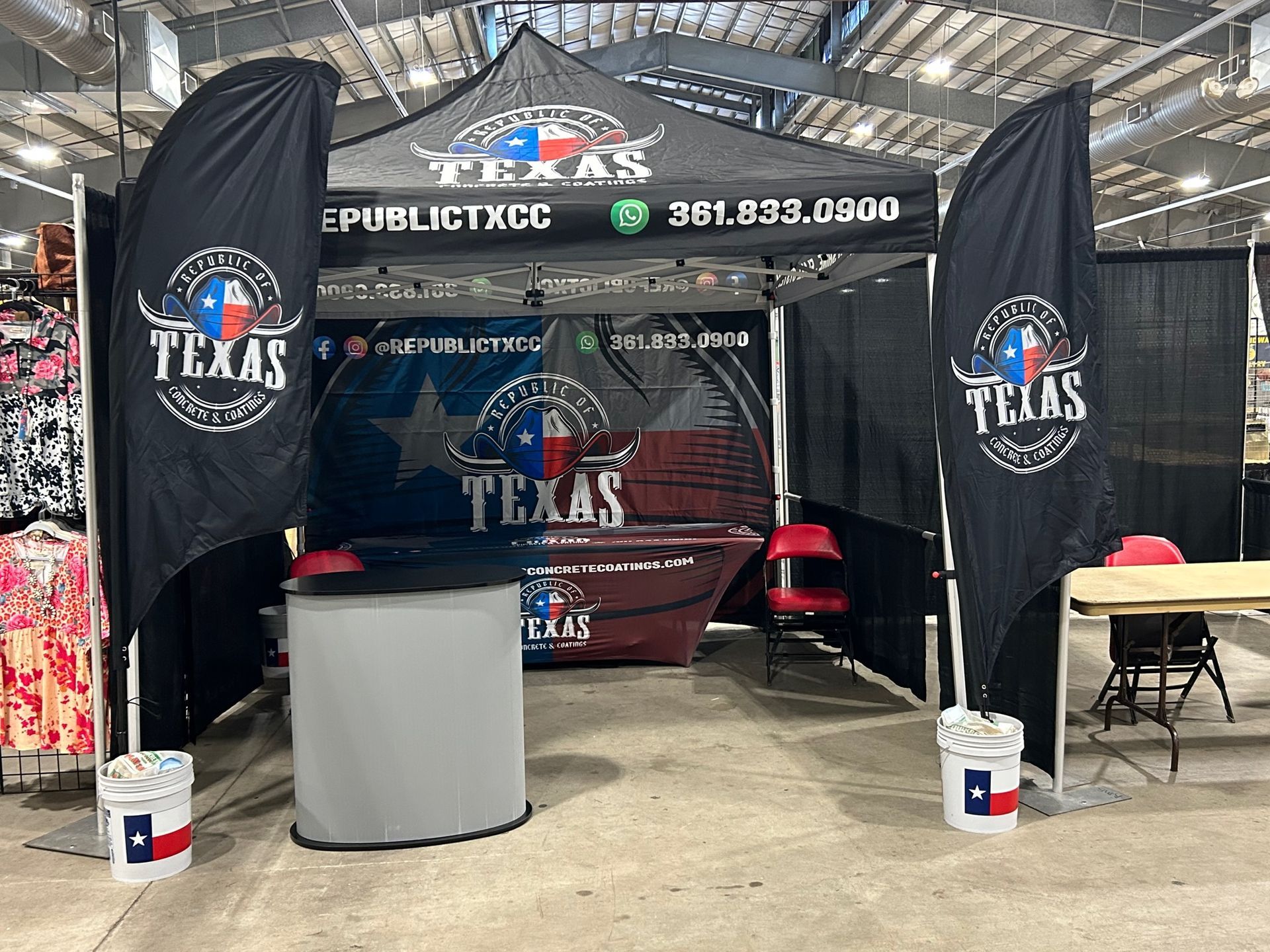 Trade show booth with Texas logo, black banners, a tent, and a table.